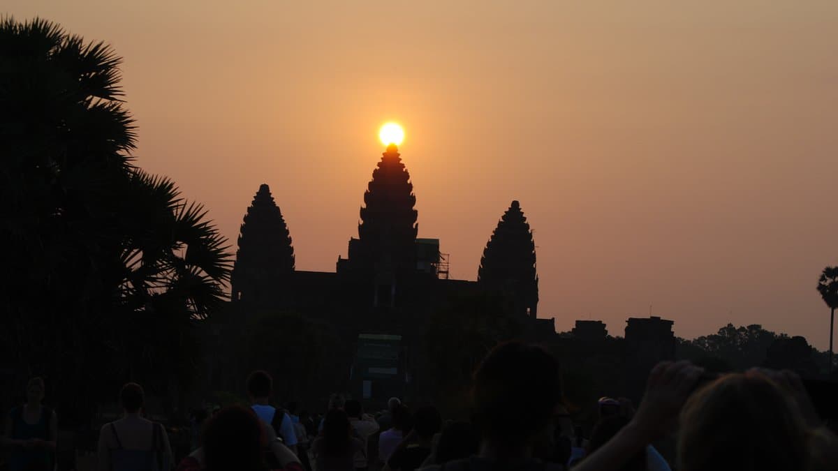 Angkor Wat towers reflected in water with the temple complex beyond.