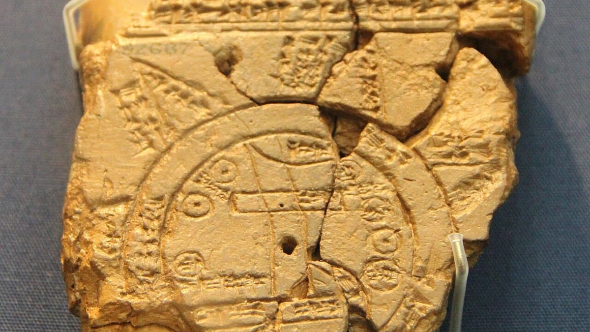 Broken clay tablet with cuneiform writing above a circular map.