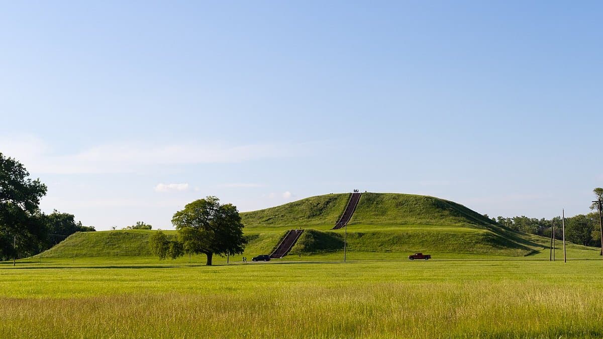 Large grass-covered stepped Monks Mound rising above the Cahokia landscape.