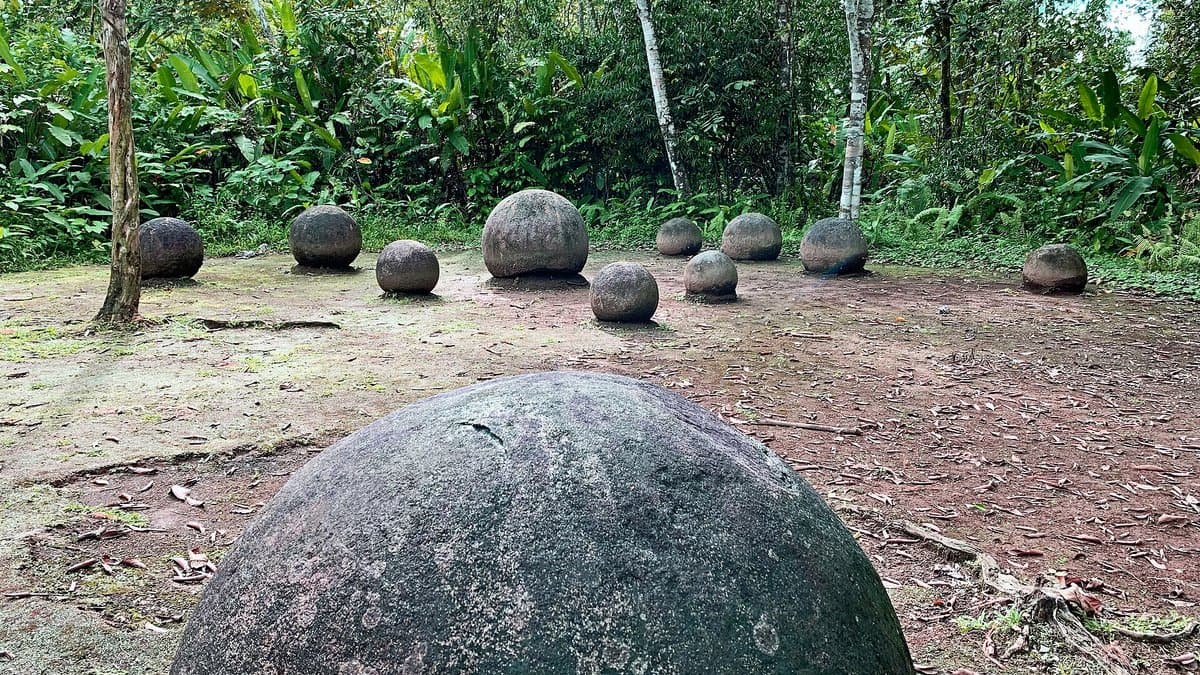 Large stone spheres in a grassy archaeological setting.