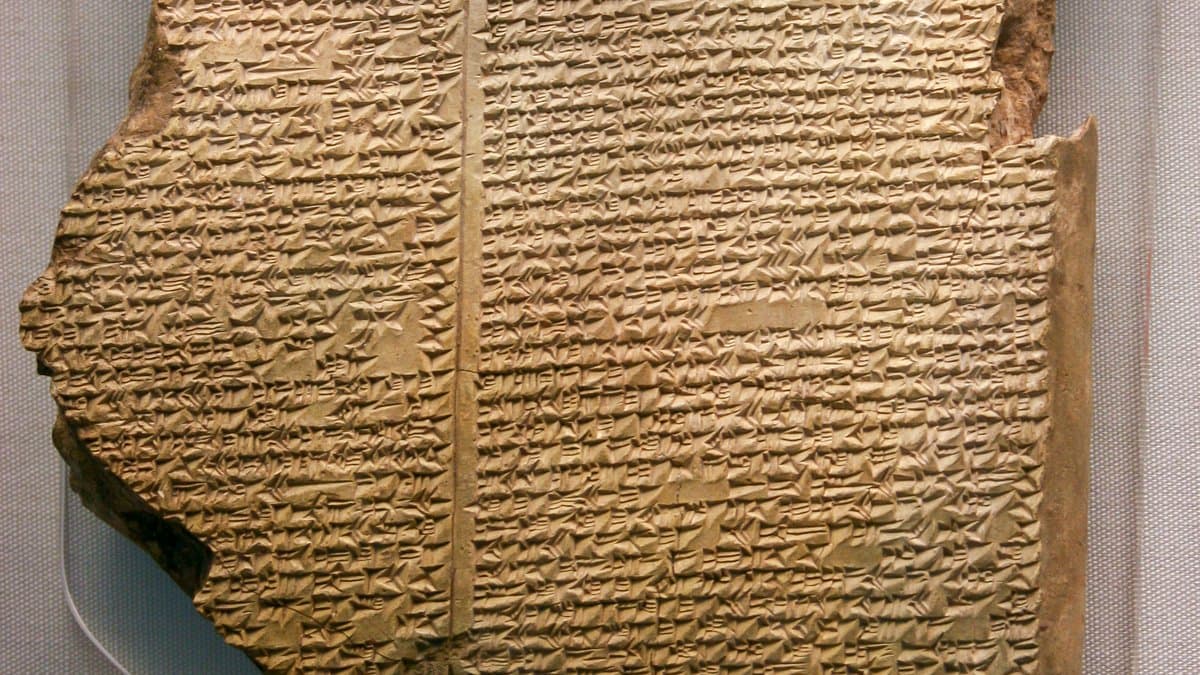 Dark, broken cuneiform tablet with closely spaced lines of wedge-shaped writing.