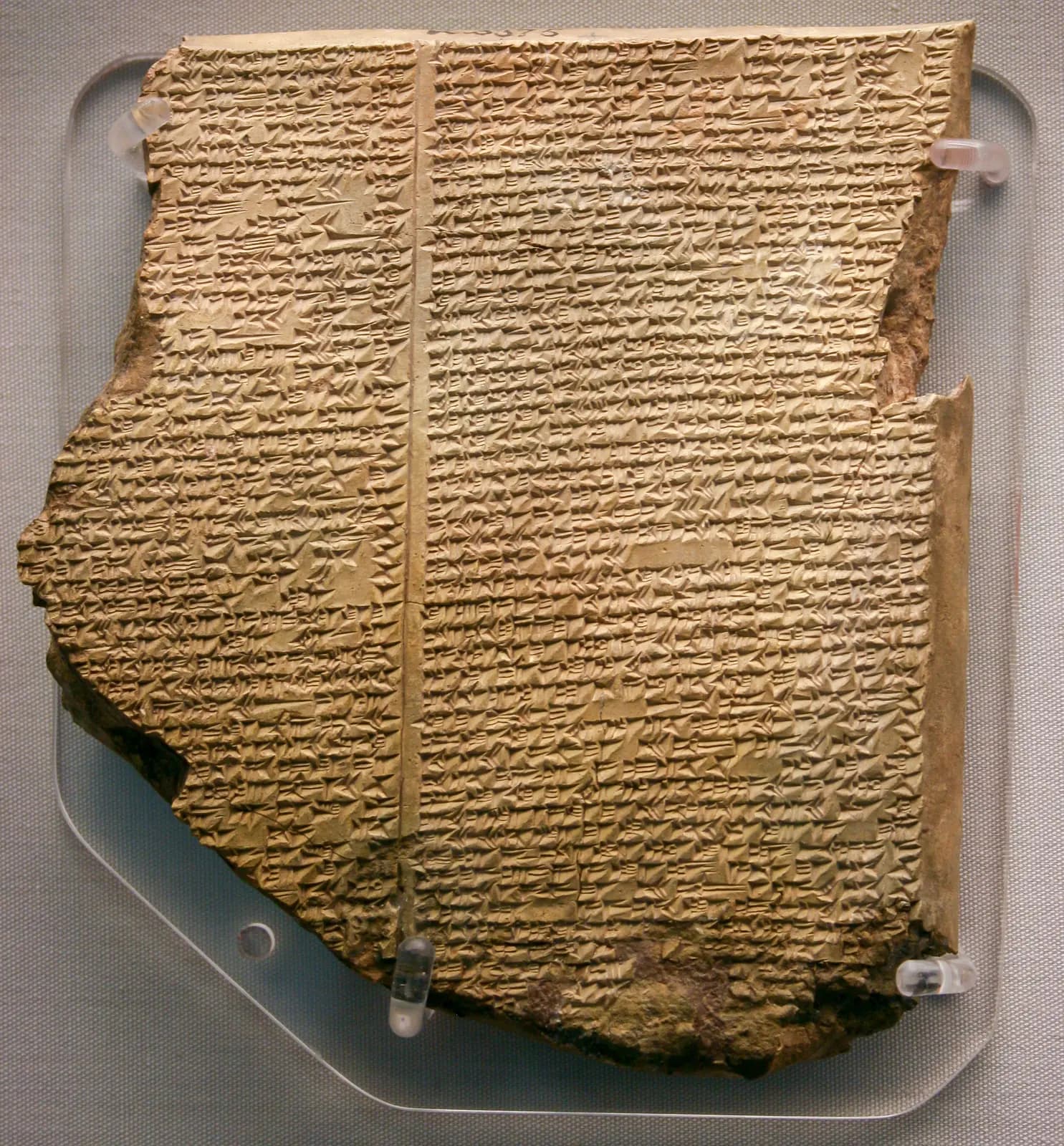 Dark, broken cuneiform tablet with closely spaced lines of wedge-shaped writing.