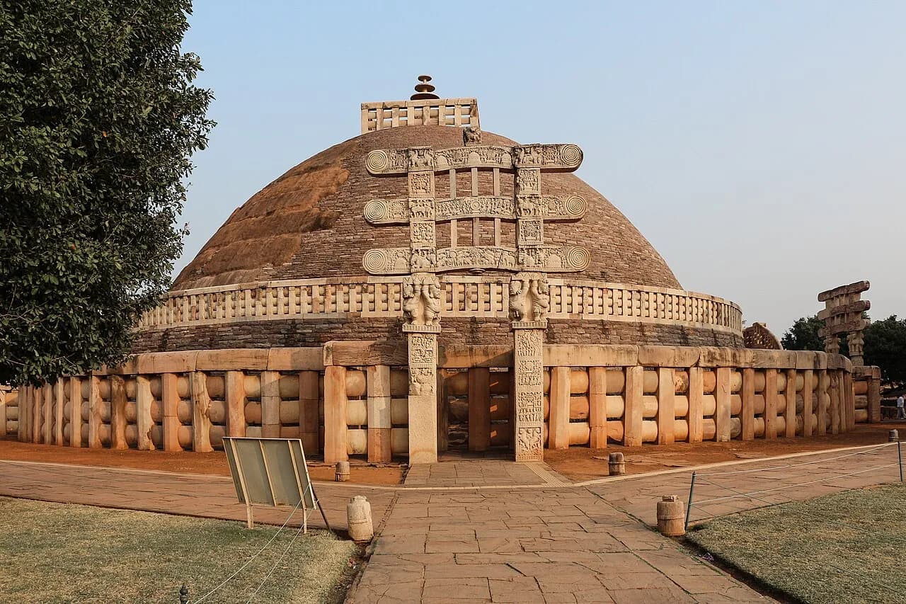 Rounded Great Stupa at Sanchi seen with one of its intricately carved stone gateways.