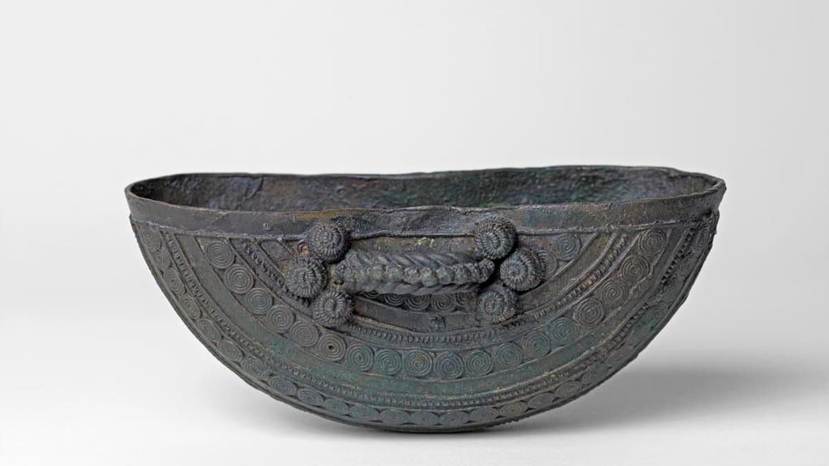 Crescent-shaped bronze bowl from Igbo-Ukwu with a twisted handle, raised bosses and rows of spirals.