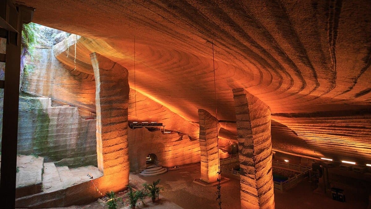 Large rock-cut chamber with pillars and patterned walls.