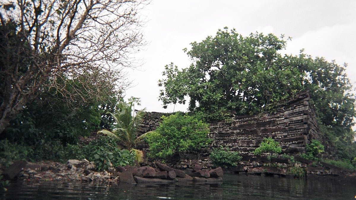 Stacked basalt columns forming a wall beside tidal water at Nan Madol.