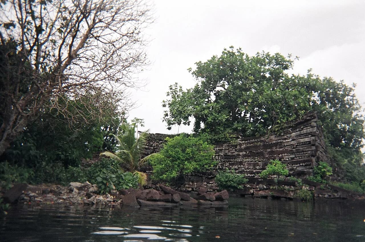 Stacked basalt columns forming a wall beside tidal water at Nan Madol.