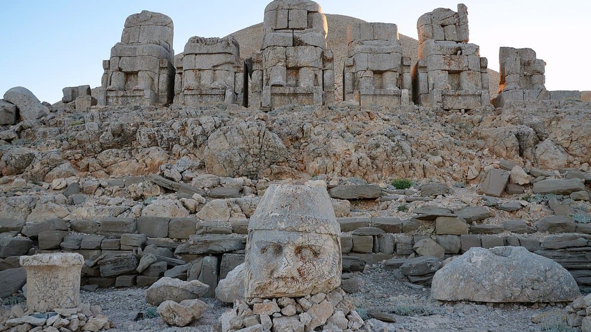 Large carved stone heads lying below seated statue bodies on Nemrut Dağ.