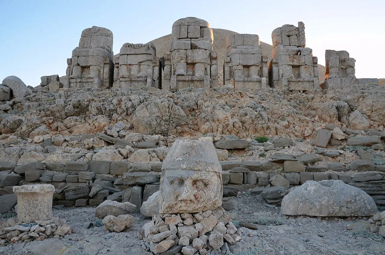 Large carved stone heads lying below seated statue bodies on Nemrut Dağ.
