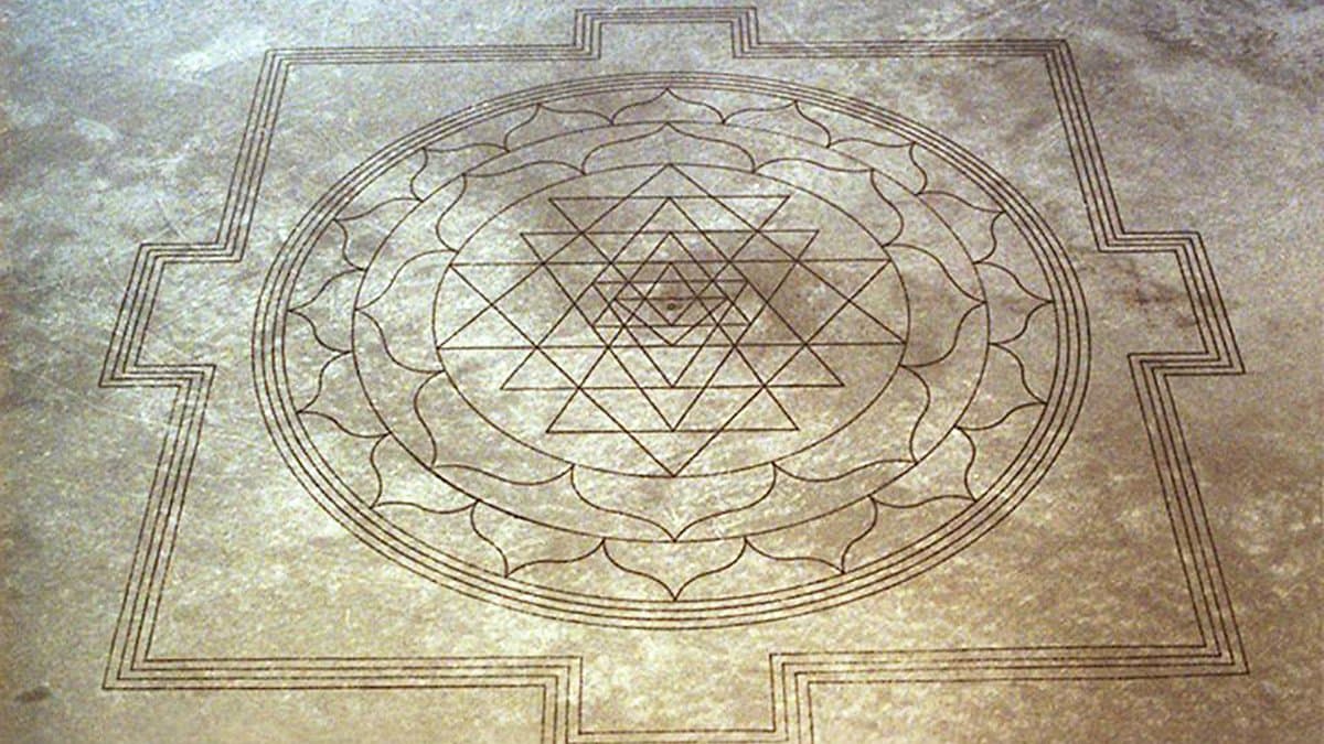 Large Sri Yantra pattern carved into pale desert ground, seen from above.