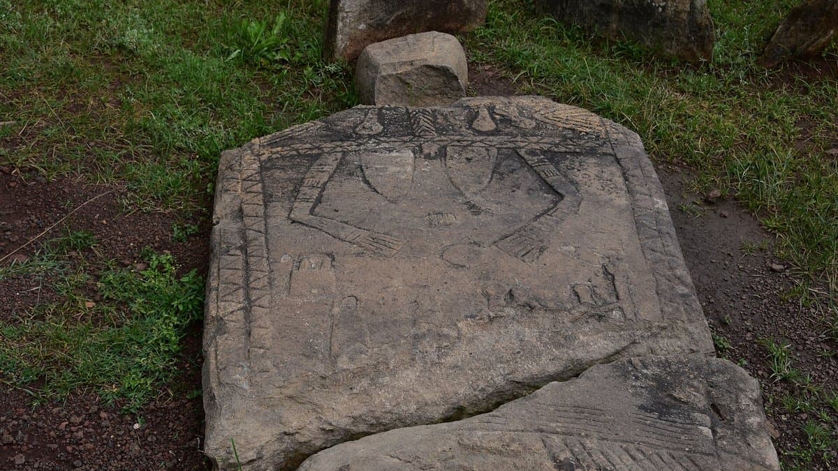 Several upright carved stones in a grassy field.