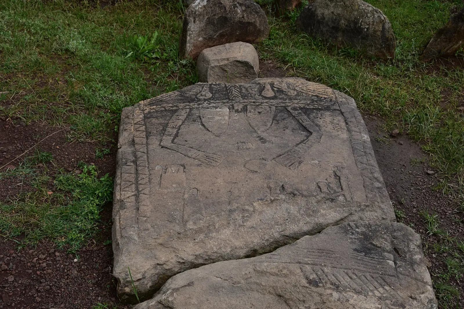 Several upright carved stones in a grassy field.