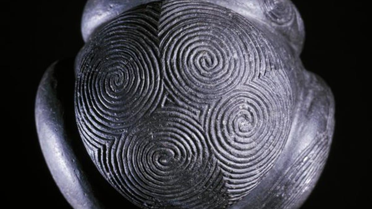 Small stone ball with rounded projections and intricate spiral carving.