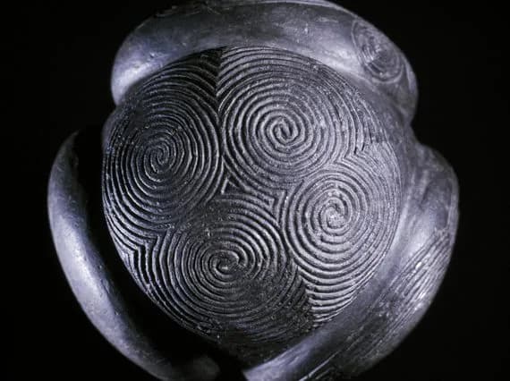 Small stone ball with rounded projections and intricate spiral carving.