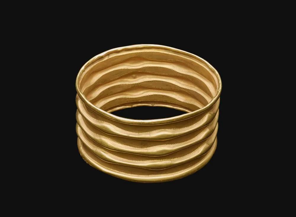Ribbed sheet-gold armlet from Lockington photographed against a dark background.